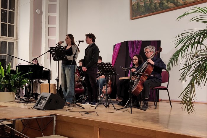 Zwei Schüler singen gemeinsam in Begleitung von Cello, Klavier und Schlagzeug einen Song vor.