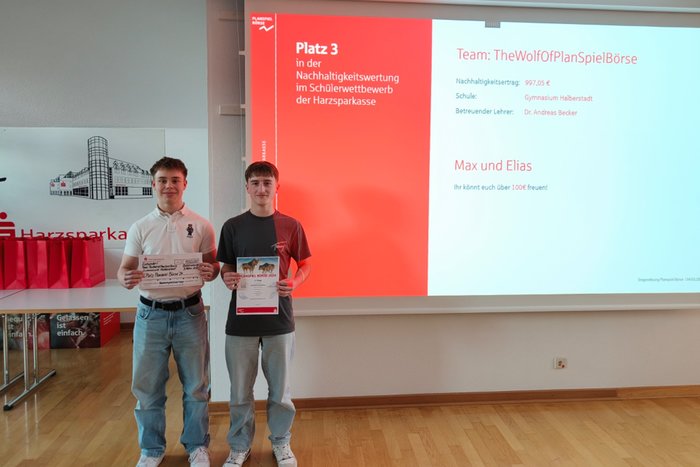 Zwei Schüler stehen mit Preis und Urkunde für ein Auszeichnungsfoto.