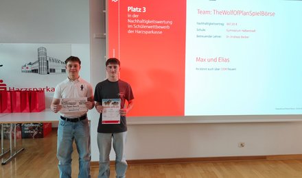 Zwei Schüler stehen mit Preis und Urkunde für ein Auszeichnungsfoto.