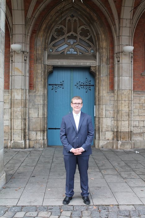 Hansi Tympel steht vor einer hölzernen Tür