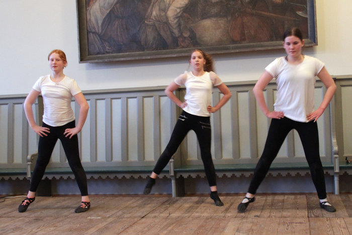 Drei Schülerinnen tanzen auf einem Holzboden