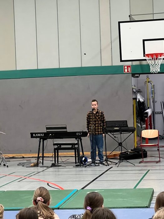 Ein Schüler steht vor einem Mikrofon